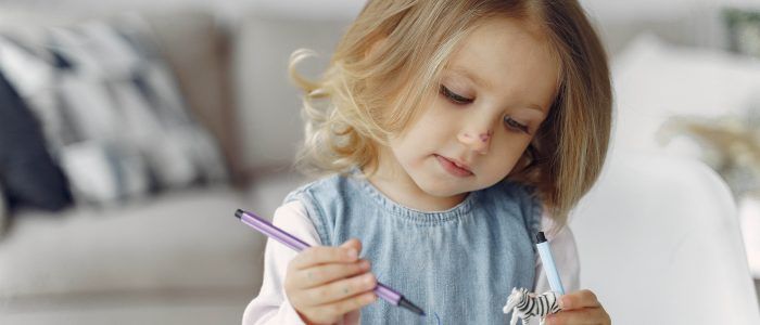 little girl sitting on a table with books WNKE59C